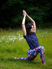 Frau in französischem Sport-Outfit mit Lotusblüten-Muster beim Yoga im Park.