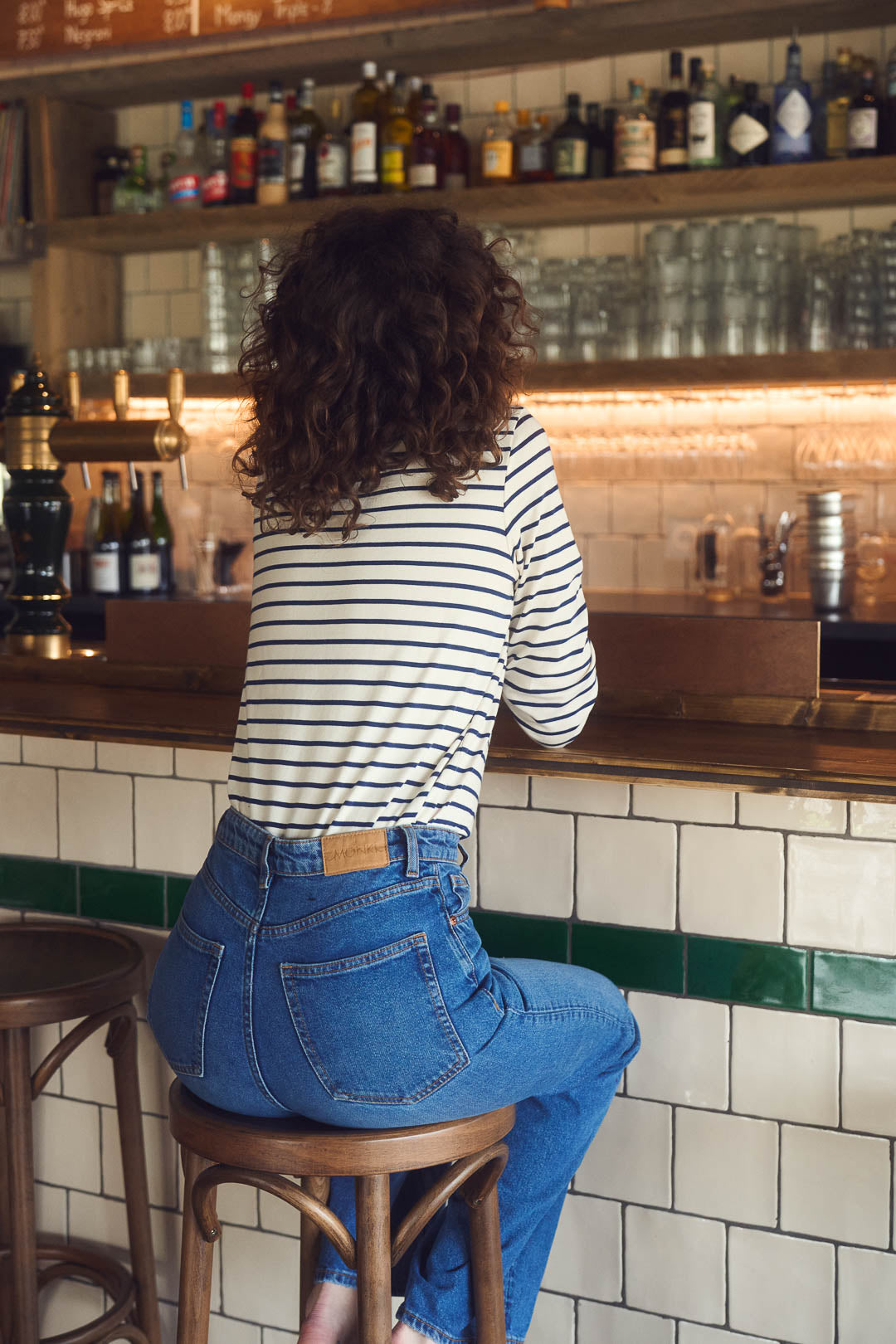 Eine Frau trägt frontal von hinten gesehen ein gestreiftes Langarmshirt aus 100 % Bio-Baumwolle. Hergestellt in Frankreich, fair produziert und nachhaltig – klassische französische Damenmode für Alltag und Büro.