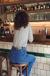 Eine Frau trägt frontal von hinten gesehen ein gestreiftes Langarmshirt aus 100 % Bio-Baumwolle. Hergestellt in Frankreich, fair produziert und nachhaltig – klassische französische Damenmode für Alltag und Büro.