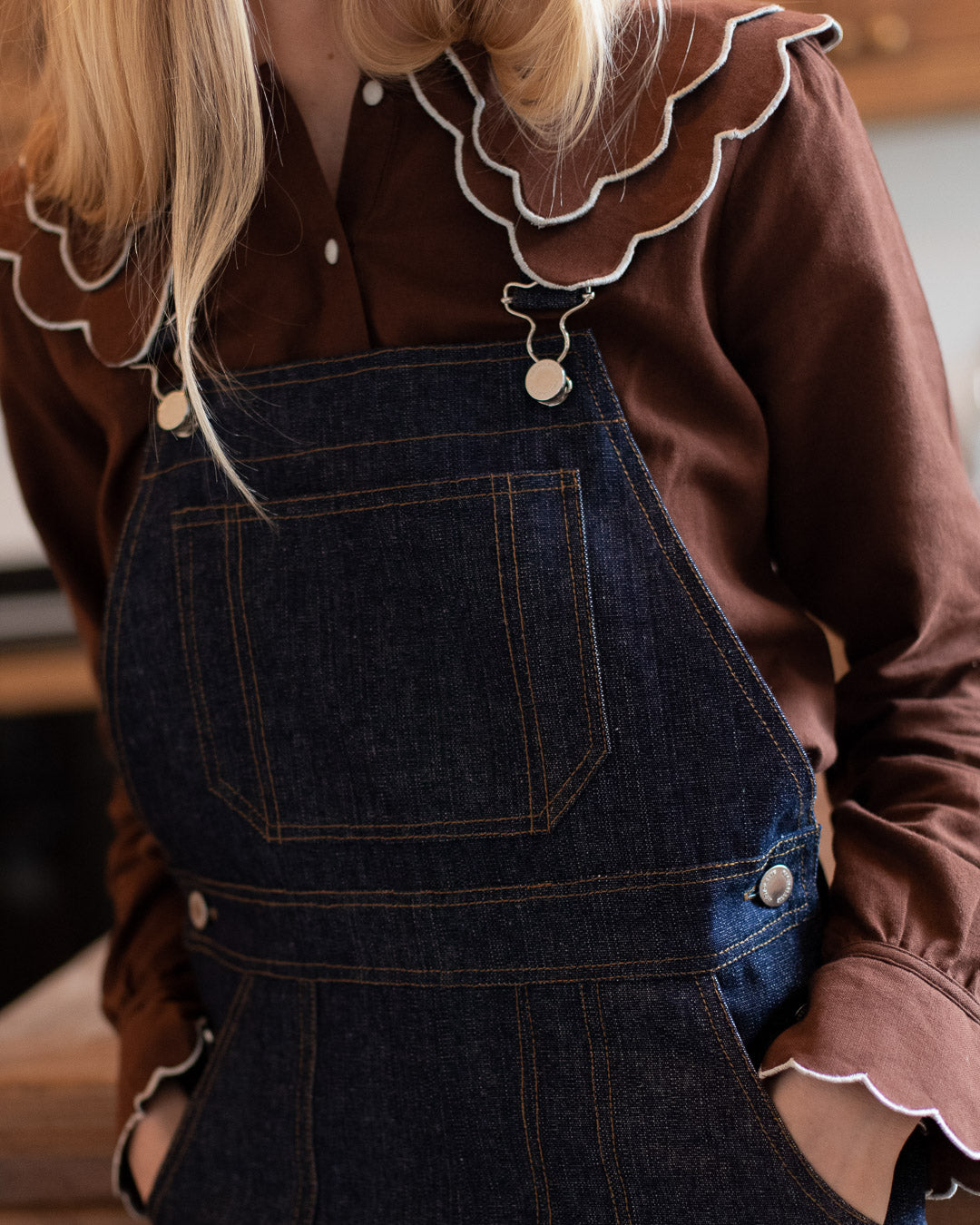 Nahaufnahme der Vorderseite einer dunkelblauen Denim-Latzhose mit Nähten und Tasche