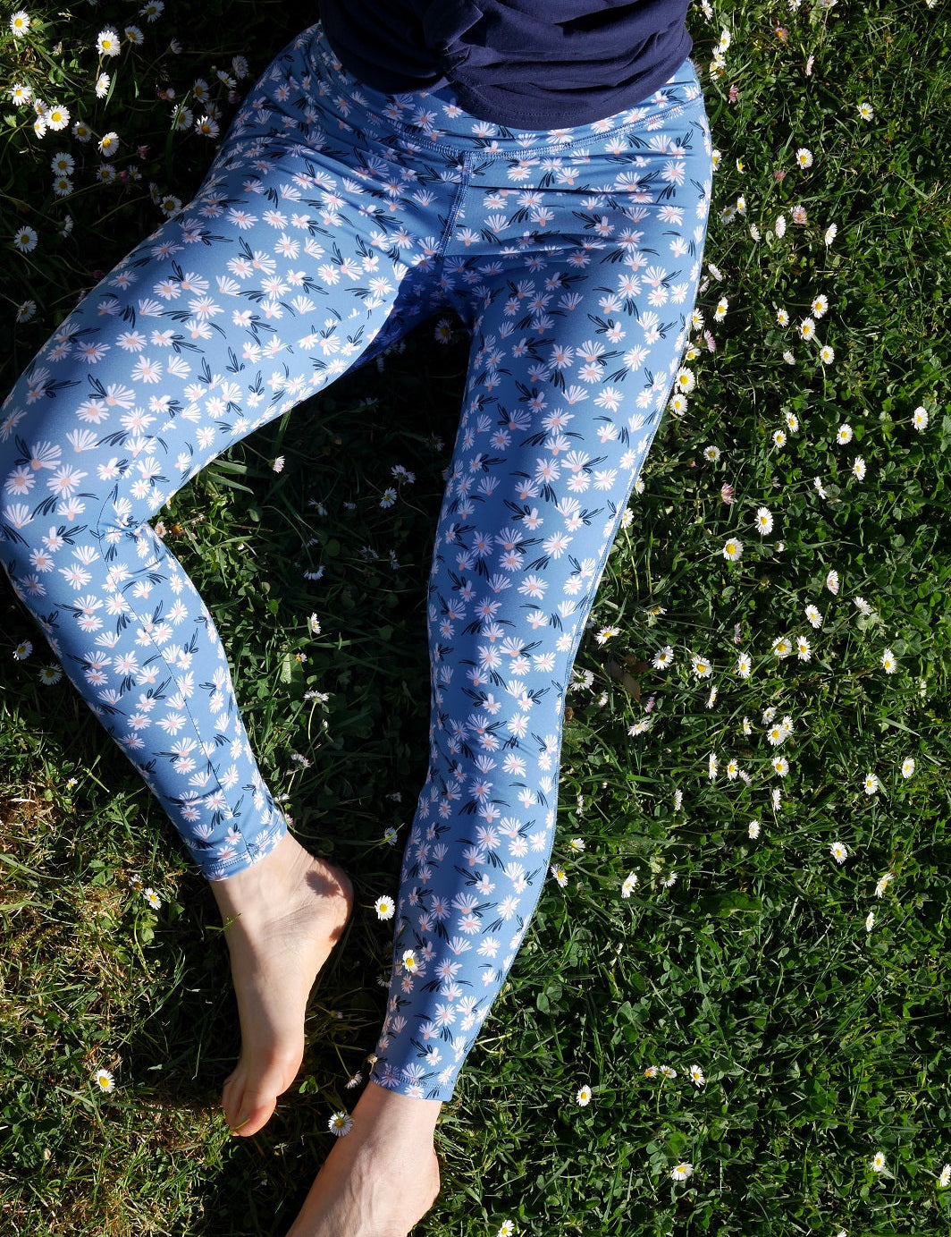 Nahaufnahme des COLIBRI-Leggings mit frischem Margeriten-Motiv, sitzend im Grünen – feines, elastisches Material für maximalen Komfort.