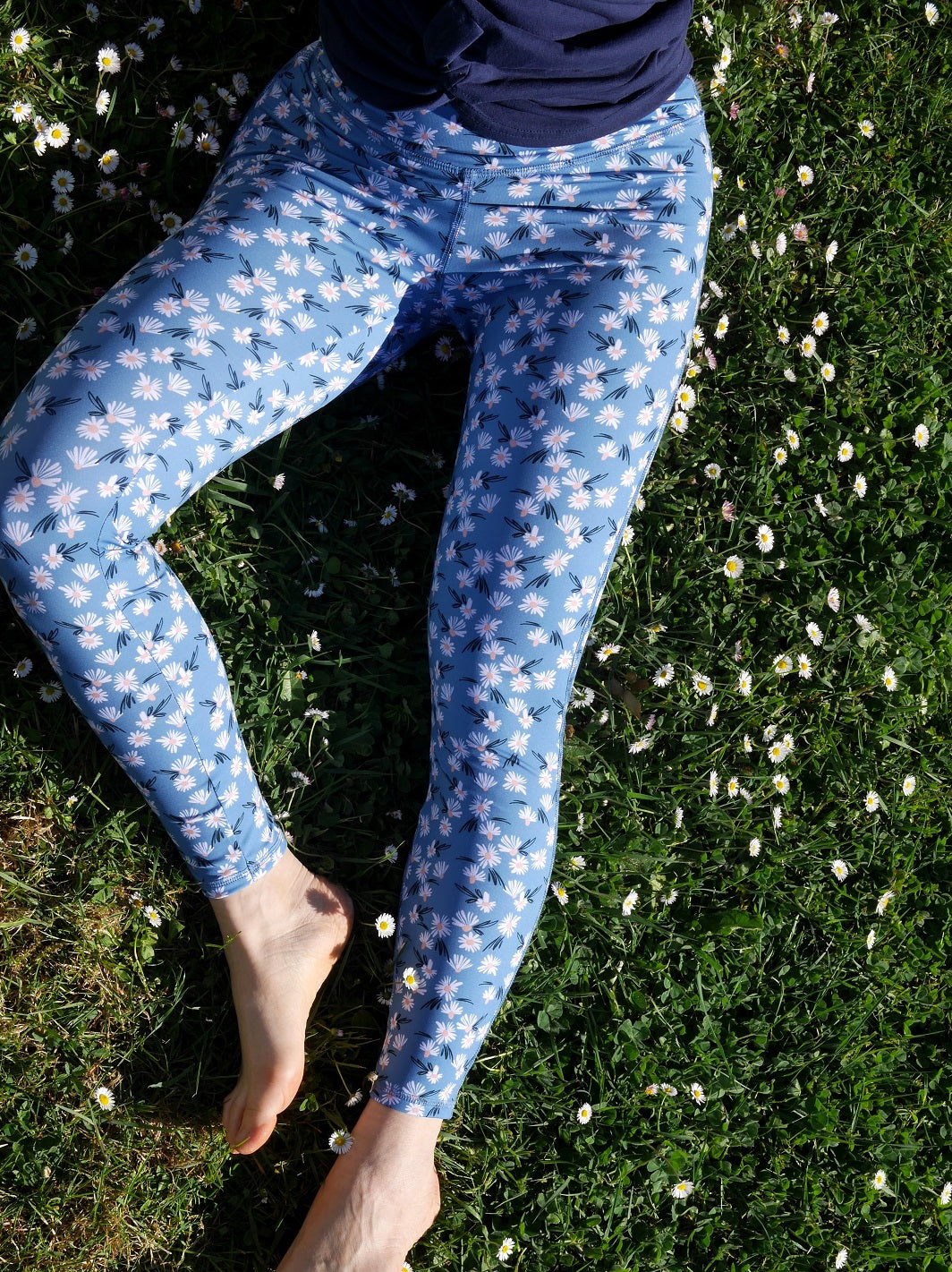 Nahaufnahme des COLIBRI-Leggings mit frischem Margeriten-Motiv, sitzend im Grünen – feines, elastisches Material für maximalen Komfort.