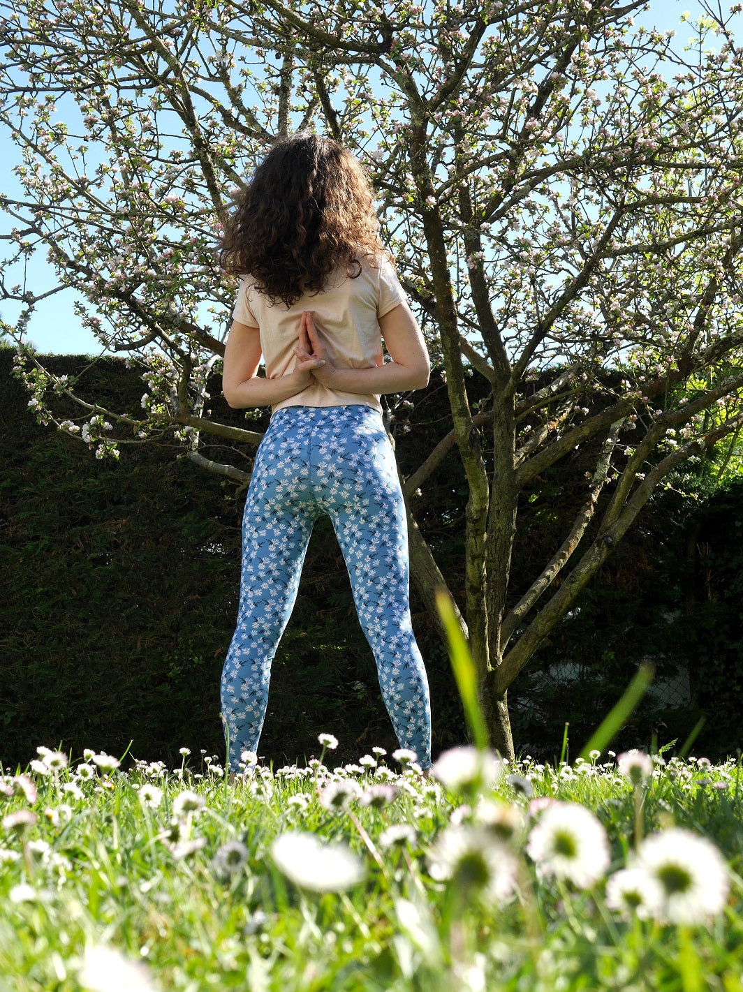 Frau von hinten, zeigt den COLIBRI-Leggings mit frischem Margeriten-Muster – passt sich perfekt jeder Bewegung an.