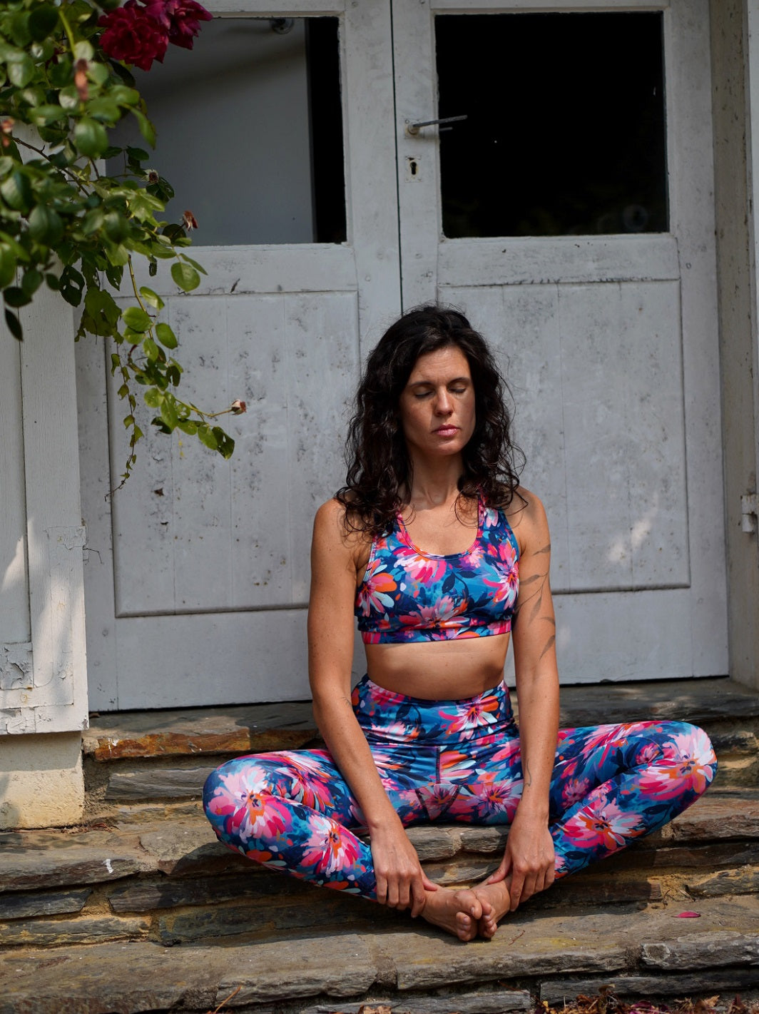 Frau sitzt im Freien in Meditationshaltung, trägt das MÉSANGE Sport-Bustier mit Lotusblüten-Motiv und die passende COLIBRI-Leggings, zeigt Ruhe, Balance und harmonischen Stil.