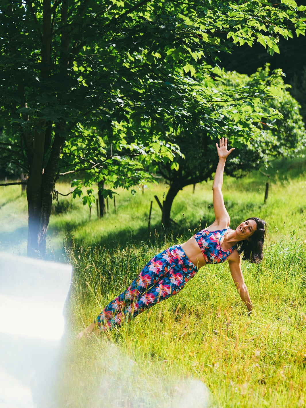 Frau trägt das MÉSANGE Sport-Bustier mit Lotusblüten-Motiv und die passende COLIBRI-Leggings beim Yoga im Freien, zeigt harmonische Bewegungen, Stil und optimalen Halt.