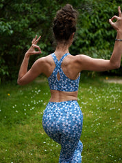 Rückenansicht des Sport-Bustiers Mésange im Margeriten-Motiv mit passendem Leggings beim Yoga im Freien.