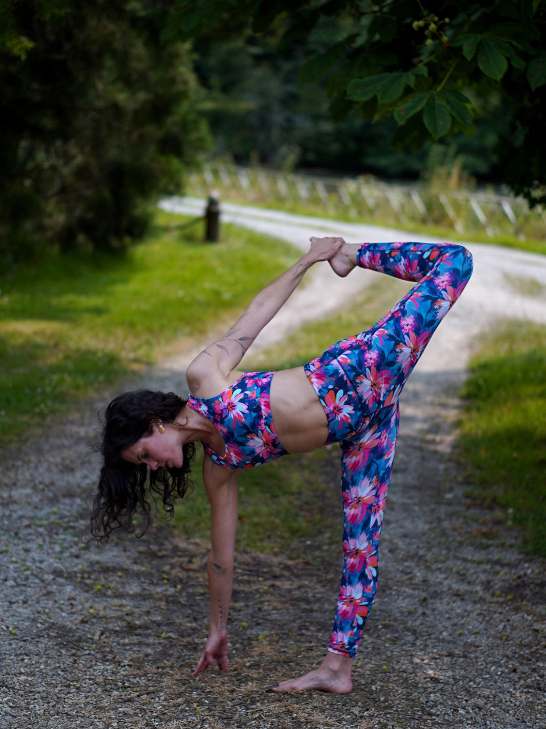 Frau trägt das nachhaltige Sport-Set mit Lotusblüten-Motiv und hält eine Yoga-Pose im Freien.