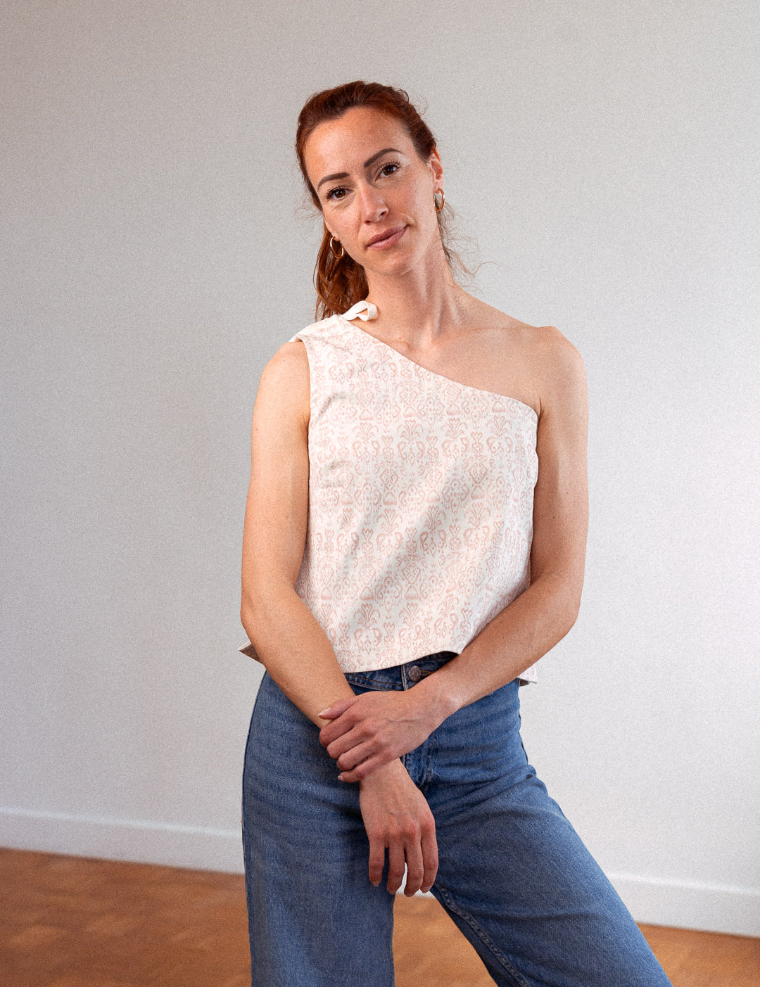 Frau steht aufrecht und trägt das asymmetrische Top "Luce" aus upgecycelter Baumwolle mit Jeans – französische Damenmode mit nachhaltigem Anspruch, elegant und alltagstauglich.