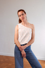 Frau steht aufrecht und trägt das asymmetrische Top "Luce" aus upgecycelter Baumwolle mit Jeans – französische Damenmode mit nachhaltigem Anspruch, elegant und alltagstauglich.