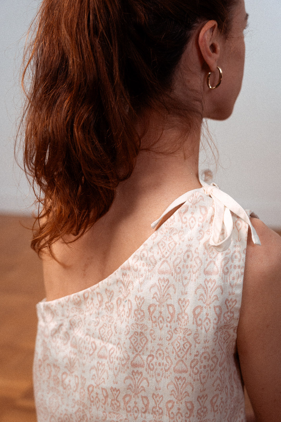 Detailansicht des asymmetrischen Tops "Luce" mit Schleife auf der Schulter – luftiges Sommer-Top aus upgecycelter Baumwolle, elegant und umweltfreundlich produziert in Frankreich.