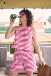 Kurztop mit rosa Vichy-Karos, getragen von einer Frau im Freien, Vorderansicht, betont den klaren, modernen Schnitt.