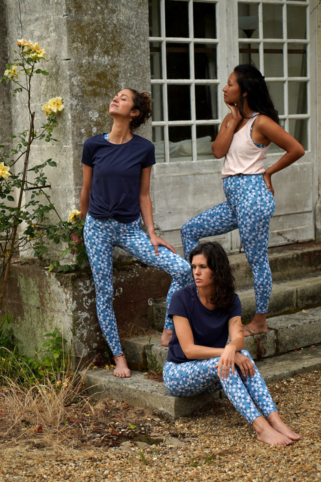 Drei Frauen im Freien, tragen den farbenfrohen COLIBRI-Leggings und das MÉSANGE-Sport-Bustier mit frischem Margeriten-Motiv.
