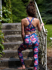 Rückansicht einer Frau im Lotusblüten-Sport-Set mit Bustier und Legging, aufgenommen im Freien.