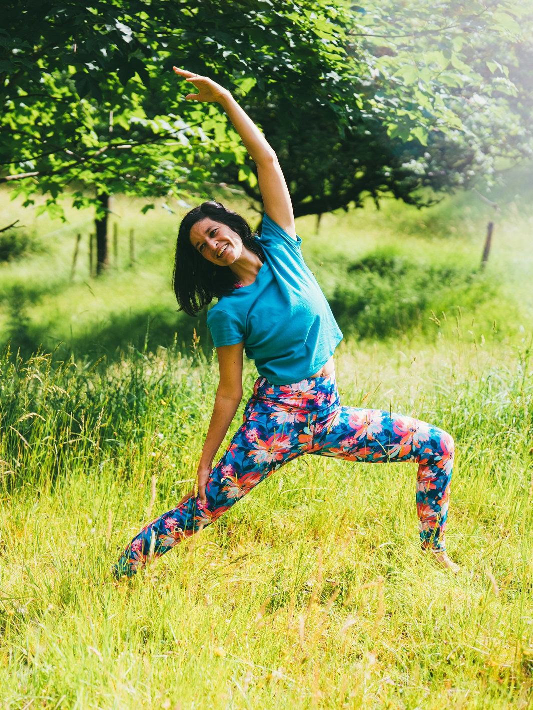 Frau trägt den Sport-Legging mit Lotusblüten-Motiv und macht eine Yoga-Pose im Freien.